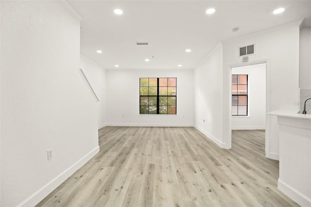 unfurnished living room with light hardwood / wood-style flooring and crown molding