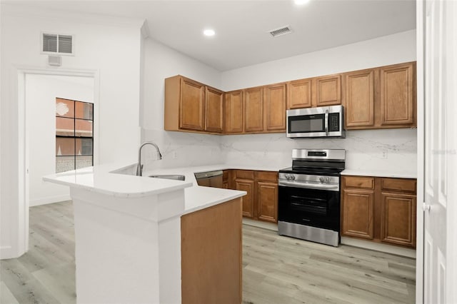 kitchen featuring sink, kitchen peninsula, backsplash, and appliances with stainless steel finishes