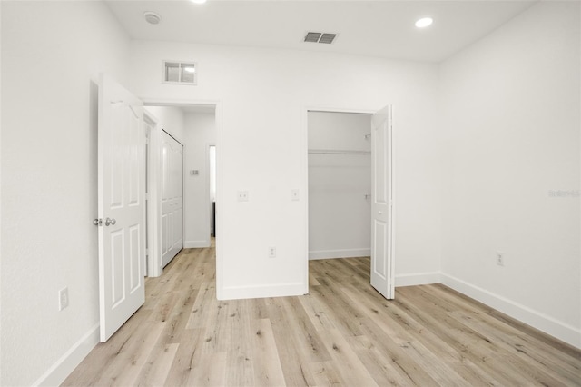 unfurnished bedroom with a walk in closet, light hardwood / wood-style floors, and a closet