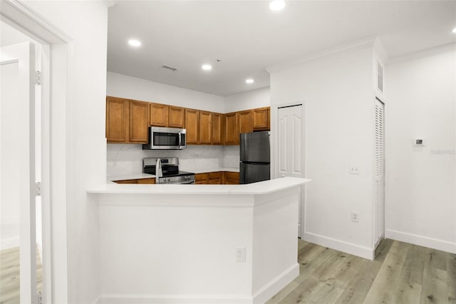 kitchen featuring stainless steel appliances, tasteful backsplash, light hardwood / wood-style flooring, kitchen peninsula, and ornamental molding