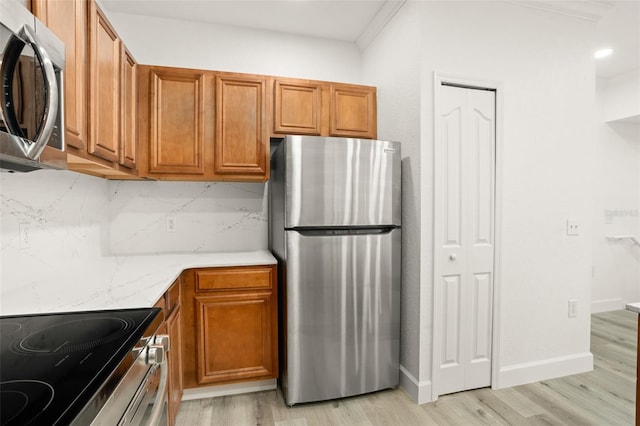 kitchen with decorative backsplash, light wood-type flooring, stainless steel appliances, and ornamental molding