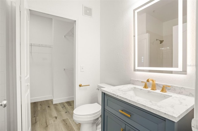 bathroom featuring a tile shower, vanity, hardwood / wood-style flooring, and toilet