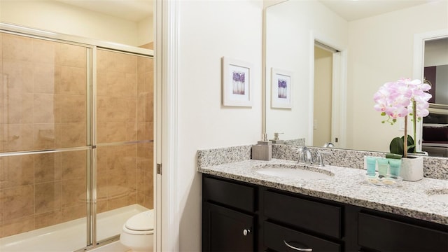 bathroom featuring an enclosed shower, vanity, and toilet