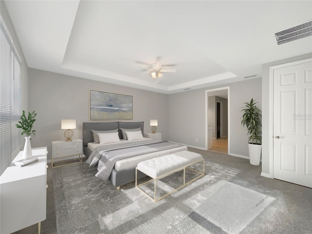 carpeted bedroom featuring a tray ceiling and ceiling fan