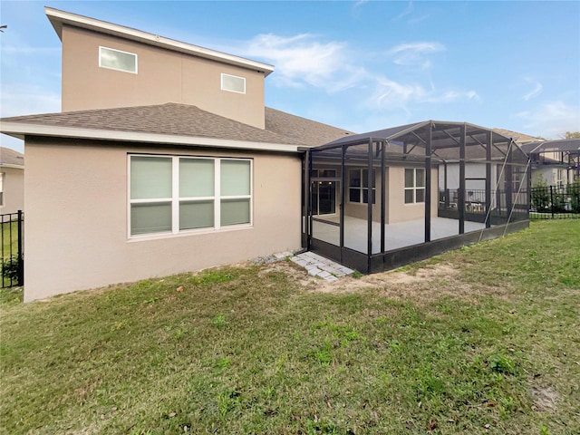 back of house featuring glass enclosure, a yard, and a patio