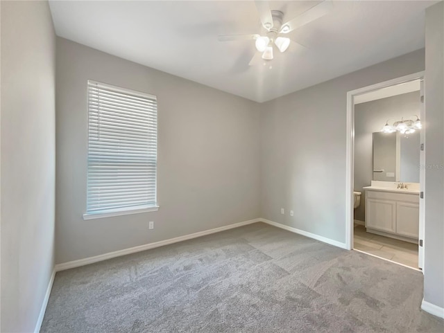 unfurnished bedroom with ensuite bath, ceiling fan, sink, and light carpet