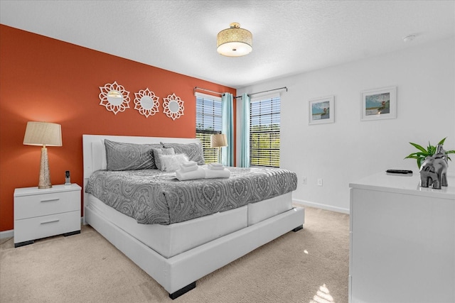 bedroom featuring light colored carpet and a textured ceiling