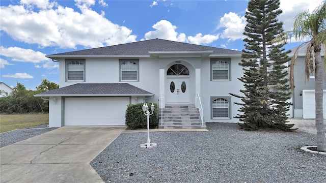 bi-level home featuring driveway, a garage, and stucco siding