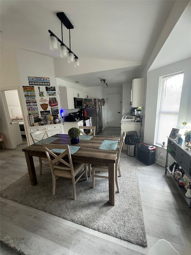 dining room with rail lighting and light hardwood / wood-style flooring