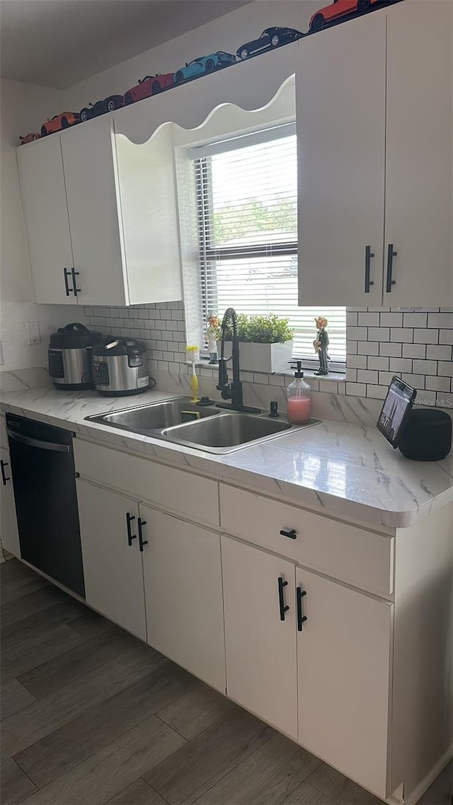 kitchen with white cabinetry, decorative backsplash, sink, dishwasher, and light stone counters