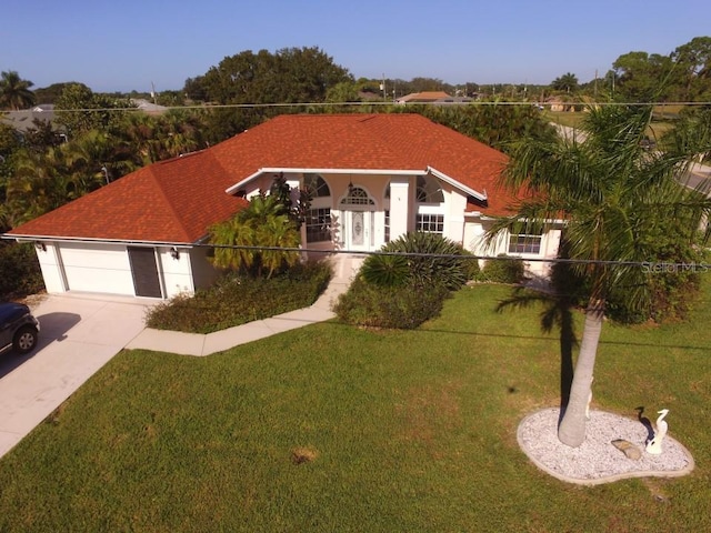 view of front of house featuring an attached garage, concrete driveway, a front yard, and a shingled roof