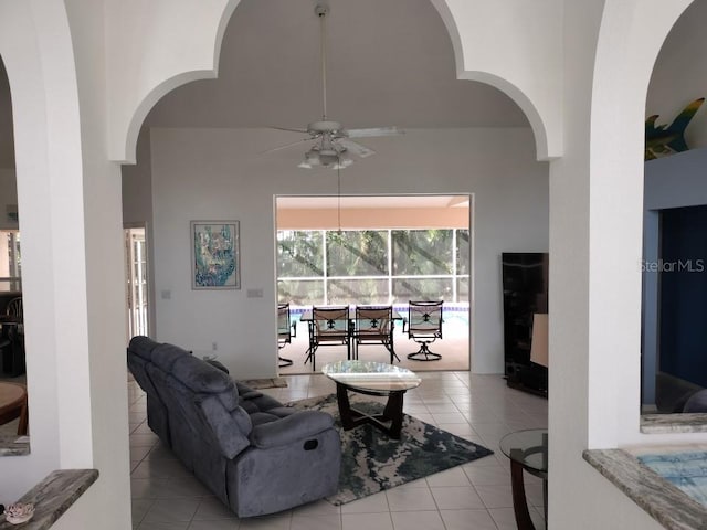 tiled living room featuring a ceiling fan and a towering ceiling