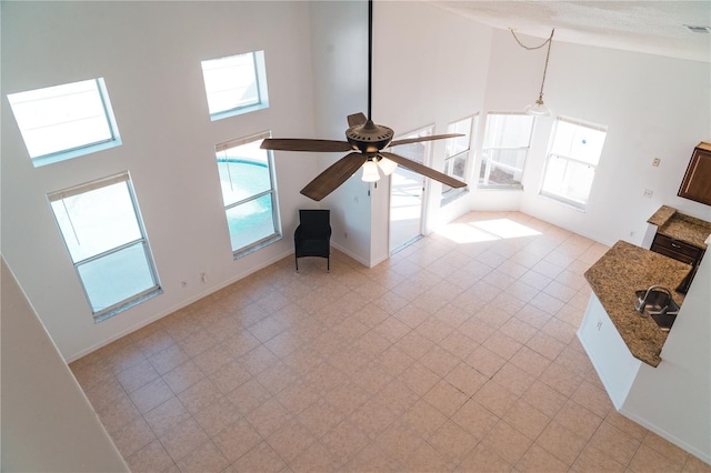 unfurnished living room featuring ceiling fan and high vaulted ceiling