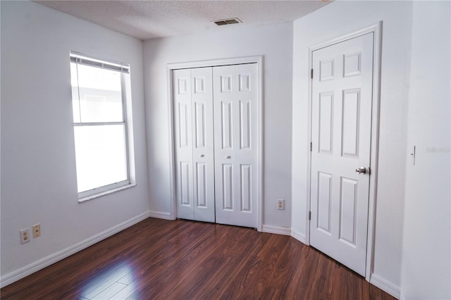 unfurnished bedroom with dark hardwood / wood-style flooring, a closet, and a textured ceiling