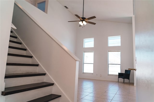 stairs featuring a high ceiling, tile patterned floors, and ceiling fan