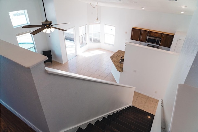 stairs featuring ceiling fan, tile patterned floors, and high vaulted ceiling