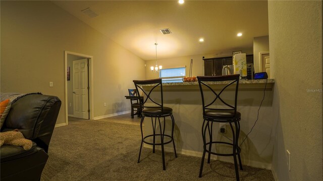 kitchen with a peninsula, a breakfast bar, visible vents, vaulted ceiling, and dark carpet