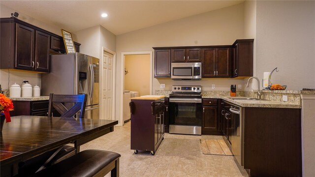 kitchen featuring dark brown cabinets, stainless steel appliances, a sink, and washing machine and clothes dryer