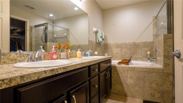 bathroom featuring tiled bath, a sink, visible vents, and a shower stall