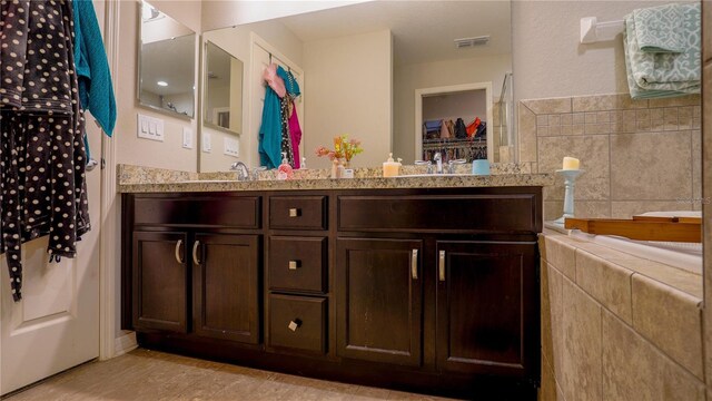 bathroom with visible vents, a sink, and double vanity