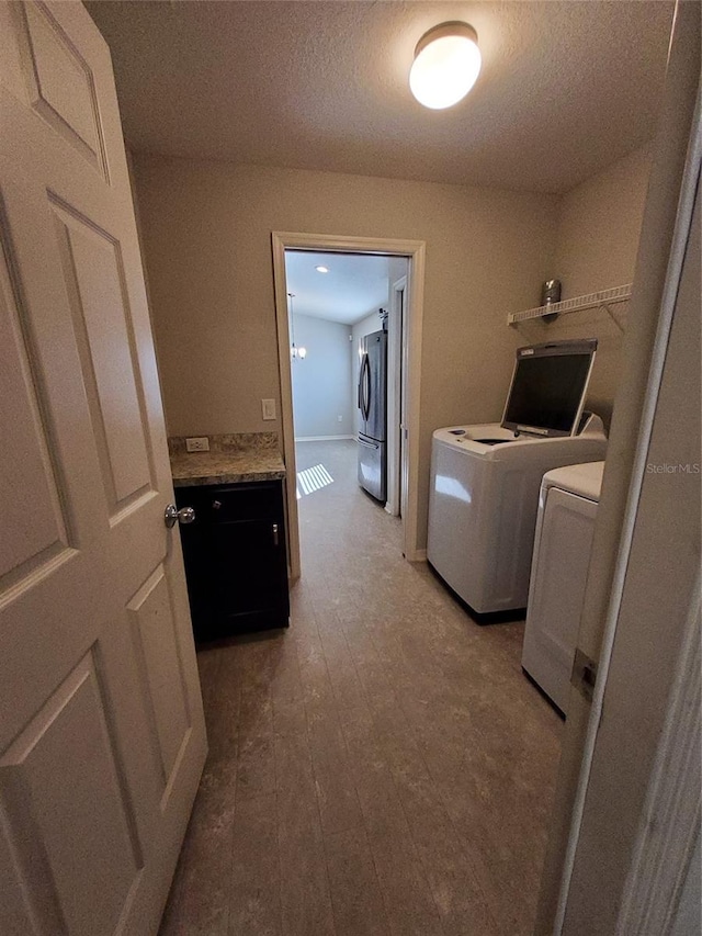 clothes washing area with laundry area, independent washer and dryer, and a textured ceiling