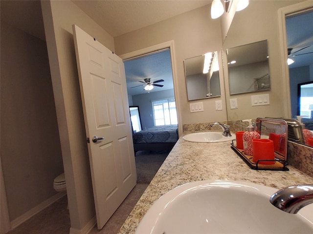 full bath featuring connected bathroom, double vanity, a sink, and a ceiling fan