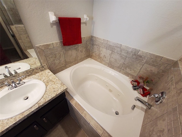 full bathroom featuring a jetted tub, a shower stall, and vanity