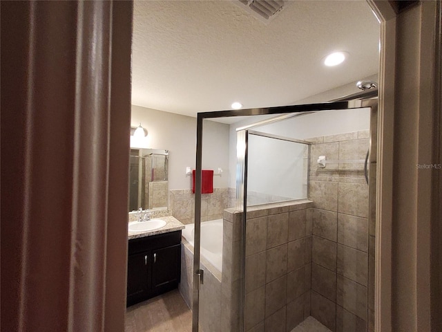 full bathroom featuring a garden tub, visible vents, a shower stall, vanity, and a textured ceiling