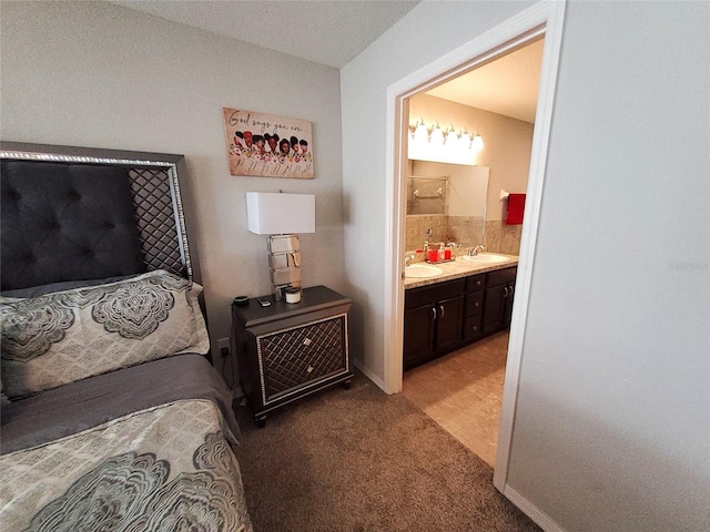 bedroom with light colored carpet, a sink, and ensuite bathroom