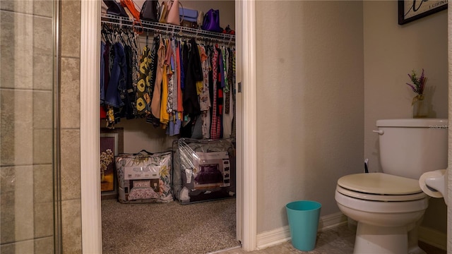 bathroom with toilet and a walk in closet