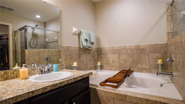 full bath with a garden tub, vanity, visible vents, a stall shower, and a walk in closet