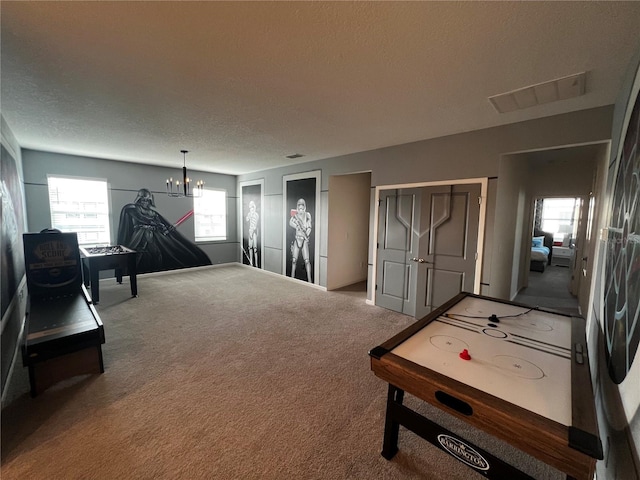 game room featuring a textured ceiling, an inviting chandelier, and carpet