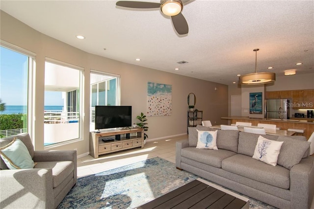 living room with light tile patterned flooring, a textured ceiling, and ceiling fan