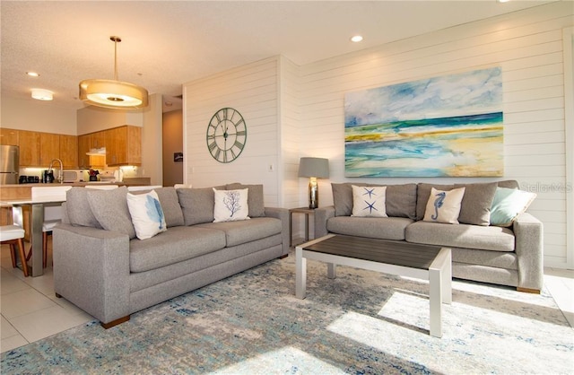 living room with wood walls, light tile patterned flooring, and sink