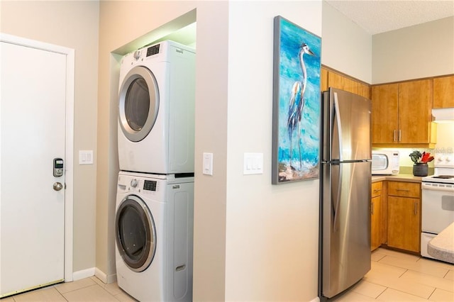 clothes washing area with light tile patterned floors and stacked washer / dryer