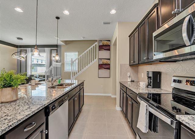 kitchen with sink, tasteful backsplash, decorative light fixtures, dark brown cabinets, and stainless steel appliances