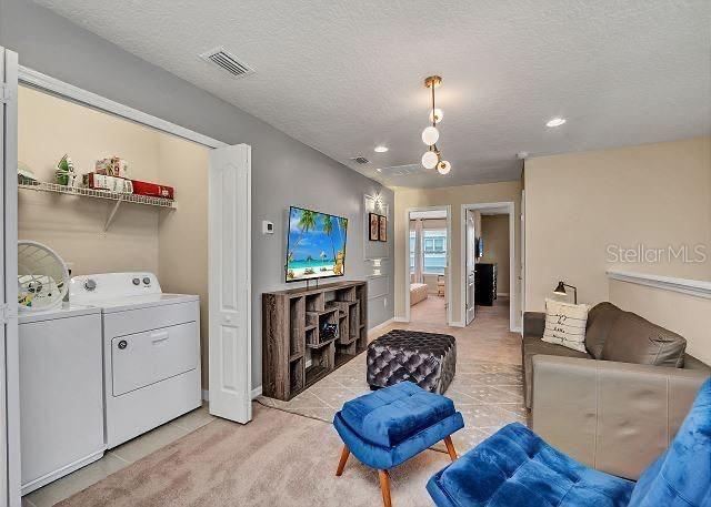 living room with washer and dryer, a textured ceiling, and light tile patterned flooring