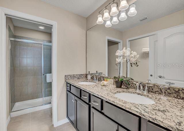 bathroom featuring tile patterned floors, vanity, and a shower with door