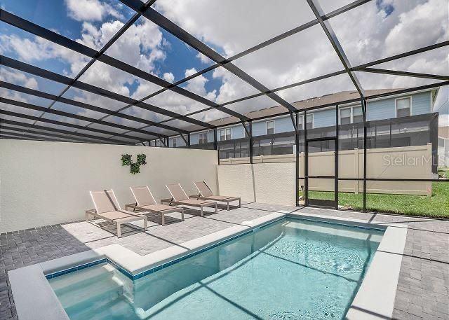 view of swimming pool featuring a patio area and glass enclosure