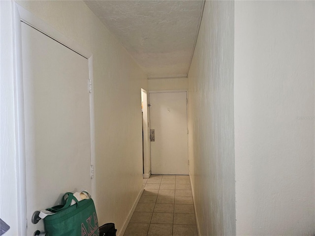 corridor featuring light tile patterned floors and a textured ceiling