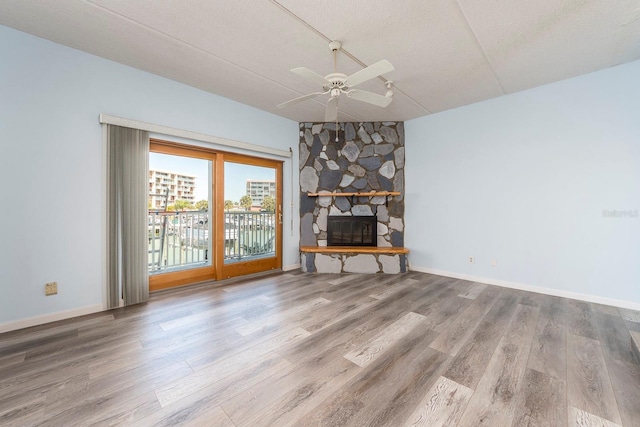 unfurnished living room featuring ceiling fan, wood-type flooring, a fireplace, and a textured ceiling