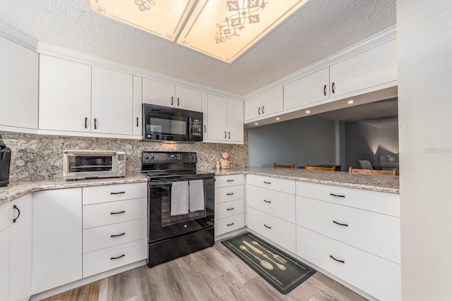 kitchen with white cabinetry, light stone countertops, light hardwood / wood-style flooring, and black appliances