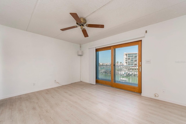 spare room with ceiling fan, a textured ceiling, and light wood-type flooring