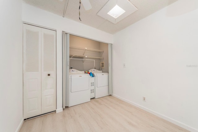 clothes washing area with a textured ceiling, light hardwood / wood-style floors, and washing machine and clothes dryer