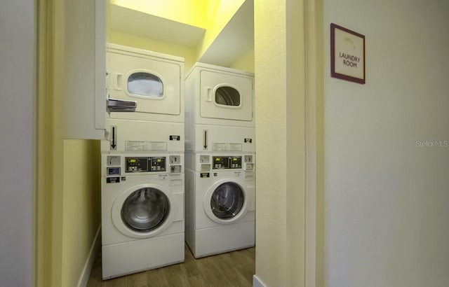 clothes washing area featuring stacked washer / drying machine, dark wood-type flooring, and washer and clothes dryer