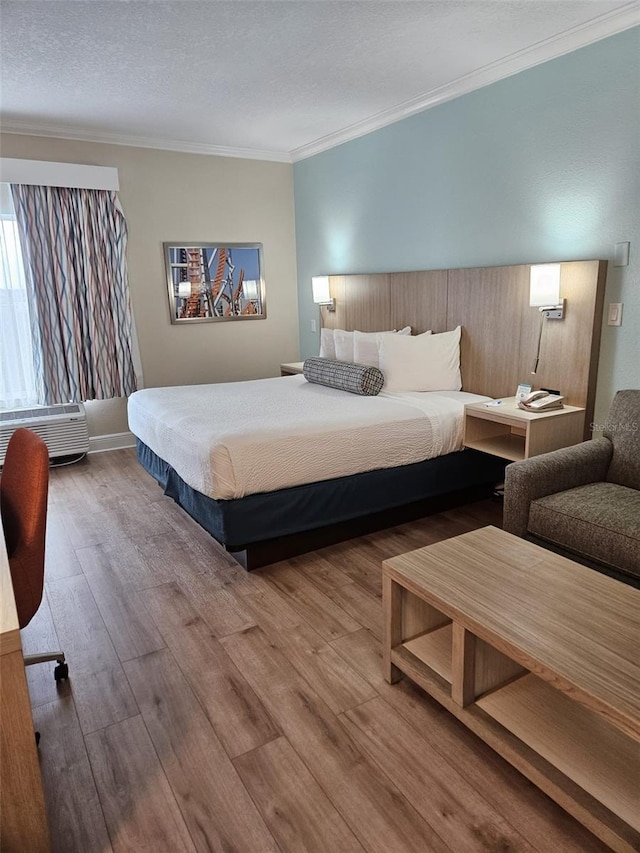 bedroom with a textured ceiling, ornamental molding, and wood-type flooring