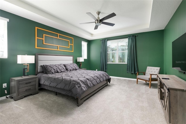 carpeted bedroom featuring ceiling fan and a raised ceiling