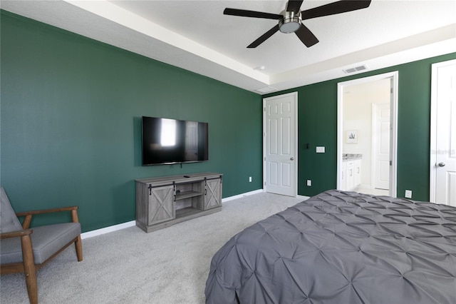 bedroom featuring ensuite bathroom, light carpet, and ceiling fan