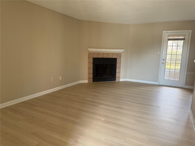 5635 Devonbriar Way Unit 103, Orlando, FL 32822 - unfurnished living room with a tile fireplace, light wood-style flooring, a textured ceiling, and baseboards