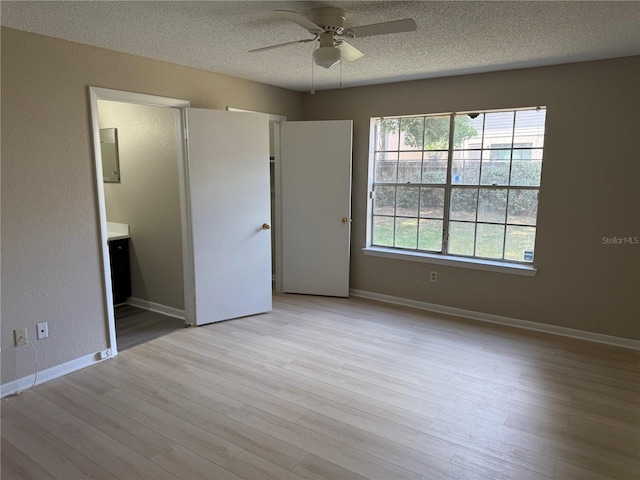 5635 Devonbriar Way Unit 103, Orlando, FL 32822 - unfurnished bedroom featuring a textured ceiling, baseboards, wood finished floors, and ensuite bath
